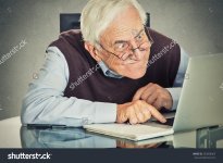 stock-photo-elderly-old-man-using-computer-sitting-at-table-isolated-on-grey-wall-background-sen.jpg