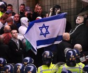 English Defence League supporters hold aloft the flag of Israel and gesture to police as they ar.jpg